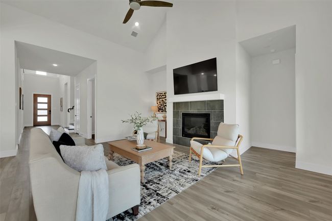 Living room with a fireplace, wood finished floors, a ceiling fan, and baseboards | Image 7