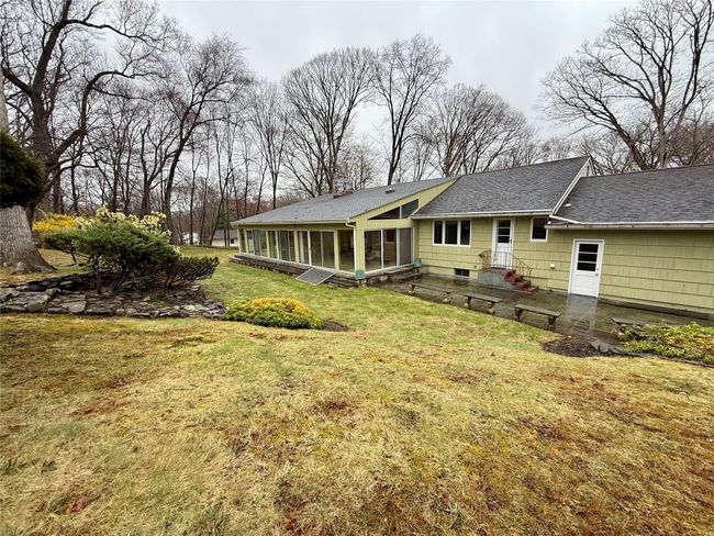 Rear view of house with a yard, a sunroom, and a shingled roof | Image 18