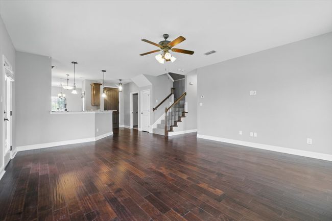 Unfurnished living room featuring ceiling fan, stairway, dark wood finished floors, and baseboards | Image 14