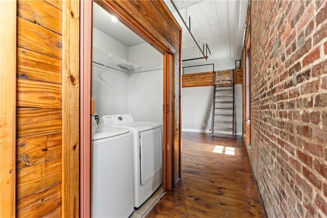 Laundry area featuring brick wall, washer and dryer, and hardwood / wood-style flooring | Image 16