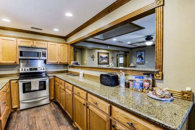 Kitchen with appliances with stainless steel finishes, ornamental molding, dark wood finished floors, light stone counters, and recessed lighting | Image 13