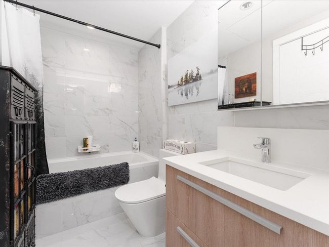 Bathroom with marble look tile flooring, shower / bath combination with curtain, vanity, and toilet | Image 18
