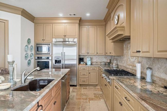 Designed for both beauty and function, this dream kitchen includes full-height cabinetry, stainless steel appliances, plentiful storage, and a walk-in pantry | Image 12