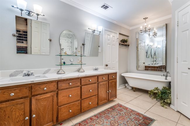 Bathroom featuring a chandelier, double vanity, ornamental molding, a freestanding bath, and tile patterned floors | Image 19