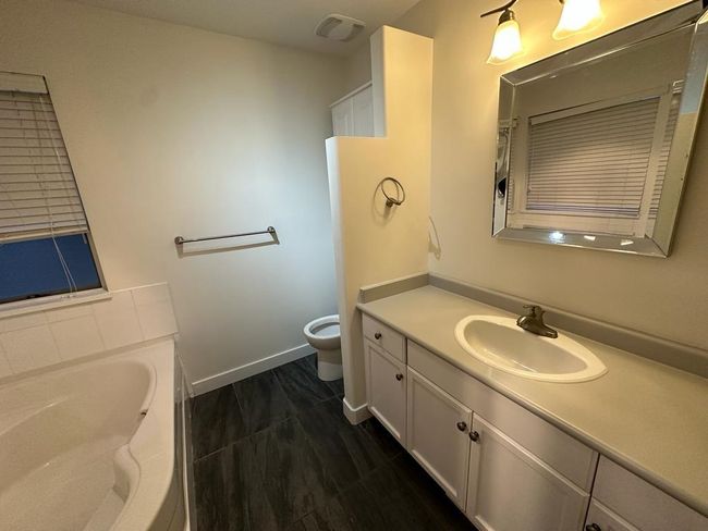 Bathroom with a garden tub, vanity, visible vents, toilet, and baseboards | Image 12