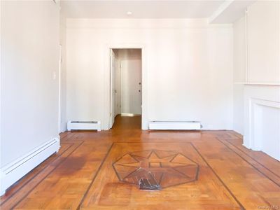 Empty room featuring a beautiful parquet style flooring and a baseboard heating unit | Image 3