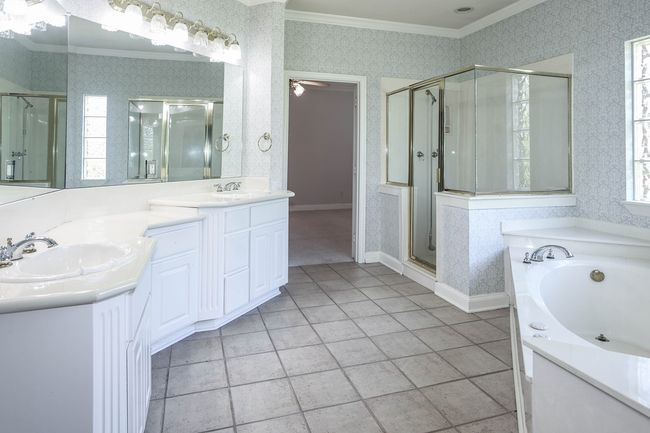 Bathroom with crown molding, wallpapered walls, a sink, and a stall shower | Image 14