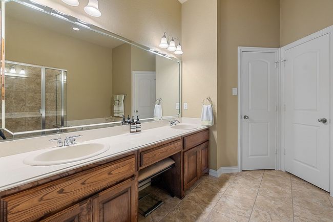 Bathroom with double vanity, a shower stall, tile patterned floors, and a sink | Image 16