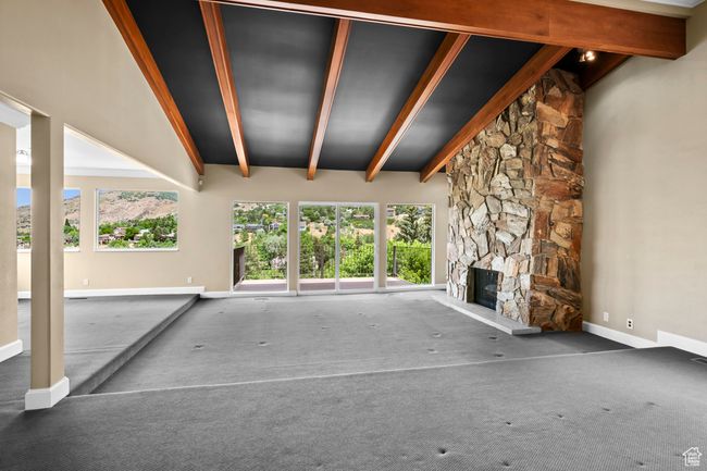 Unfurnished living room featuring carpet flooring, plenty of natural light, and a stone fireplace | Image 10