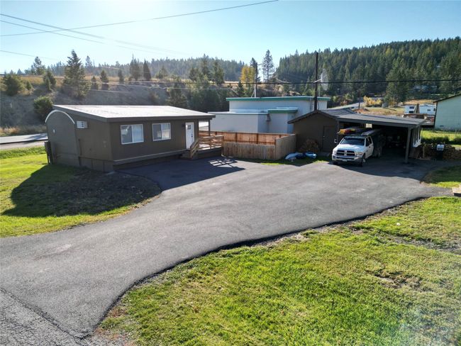 View of front of home with a front yard, a wooded view, a carport, and driveway | Image 21