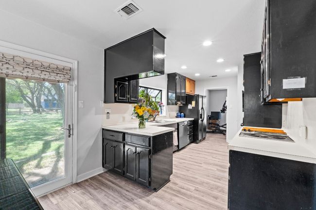 Kitchen with light countertops, black fridge, light wood-style floors, and dishwasher | Image 8