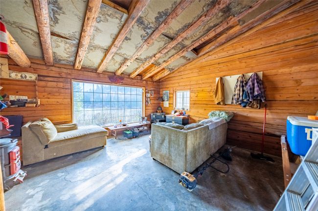 Living room featuring concrete flooring, lofted ceiling, and wood walls | Image 21