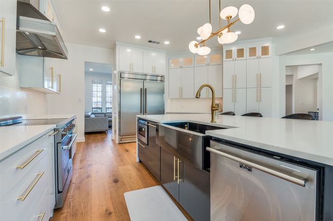 Kitchen featuring light countertops, visible vents, wall chimney range hood, light wood-style flooring, and premium appliances | Image 7