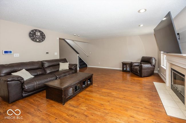 living area with a fireplace, light wood finished floors, stairs, and recessed lighting | Image 7