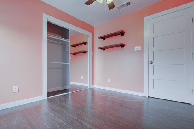 Unfurnished bedroom featuring ceiling fan, a closet, visible vents, wood finished floors, and baseboards | Image 13