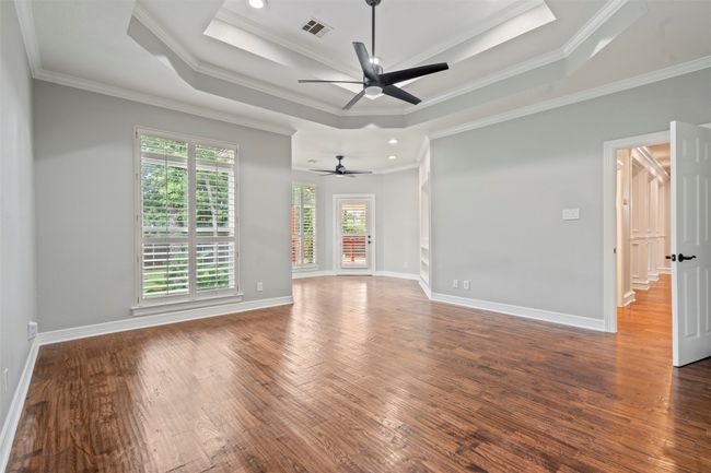 Spare room featuring ceiling fan, wood finished floors, ornamental molding, a raised ceiling, and baseboards | Image 8