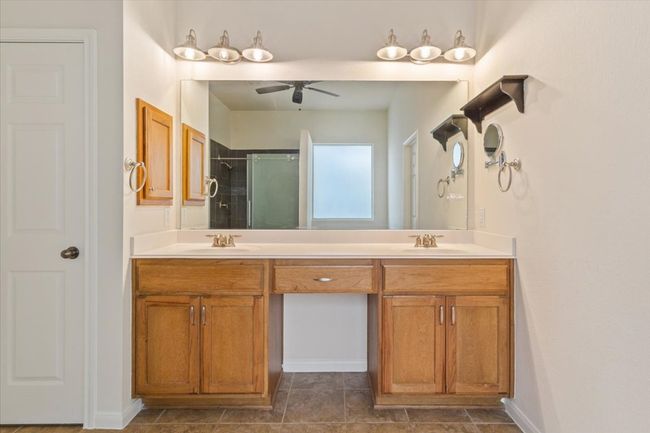 Bathroom with double vanity, a ceiling fan, and a shower with shower door | Image 19