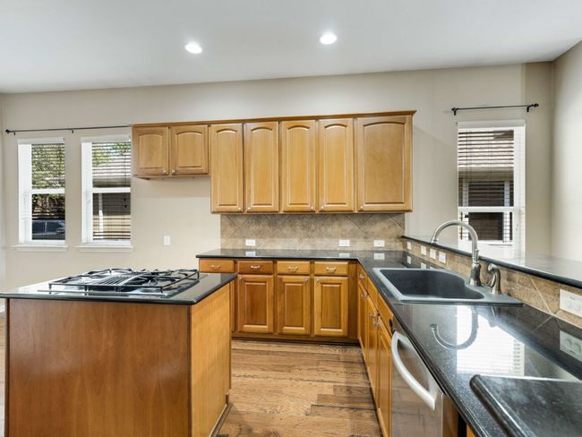 Kitchen featuring stainless steel dishwasher, black gas stovetop, dark countertops, light wood-style floors, and recessed lighting | Image 14