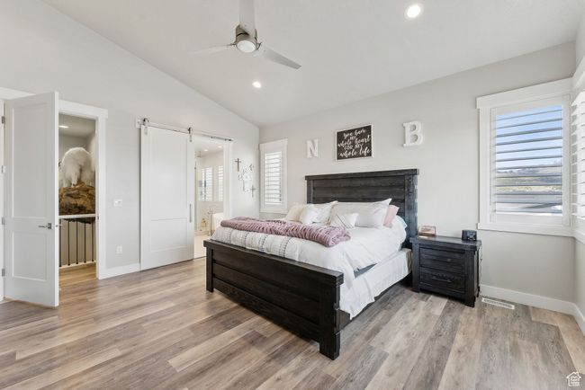 Bedroom with recessed lighting, a barn door, light wood-type flooring, visible vents, and lofted ceiling | Image 12