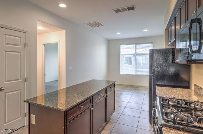 Kitchen featuring light tile patterned floors, black appliances, a kitchen island, and visible vents | Image 18