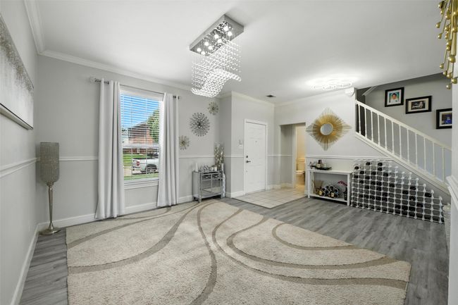 Living area featuring stairs, a chandelier, wood finished floors, and ornamental molding | Image 7