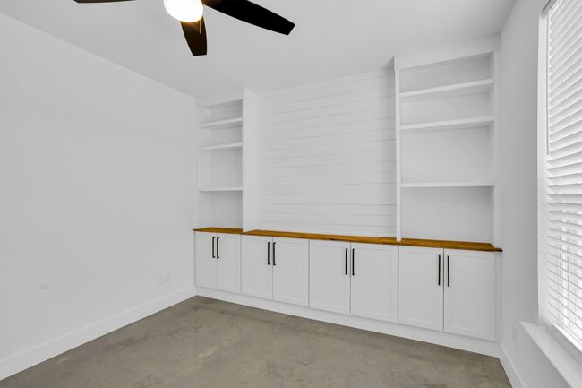 Empty room with a ceiling fan, concrete floors, and baseboards | Image 13