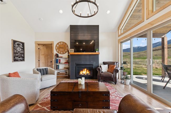 Living room featuring a large fireplace, high vaulted ceiling, a chandelier, and wood finished floors | Image 25