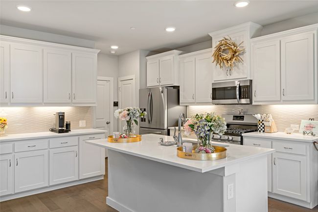 Kitchen featuring decorative backsplash, stainless steel appliances, a center island with sink, dark hardwood / wood-style floors, and white cabinetry | Image 9