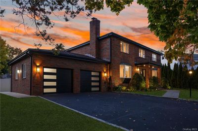 View of front facade with a balcony, a garage, and a lawn | Image 2