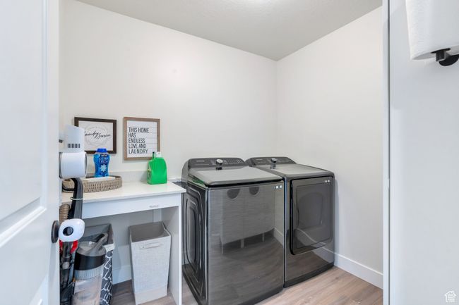 Washroom featuring baseboards, light wood-type flooring, washer and clothes dryer, and laundry area | Image 24