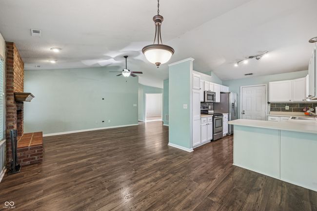 kitchen featuring stainless steel appliances, open floor plan, lofted ceiling, backsplash, and dark wood-style flooring | Image 10