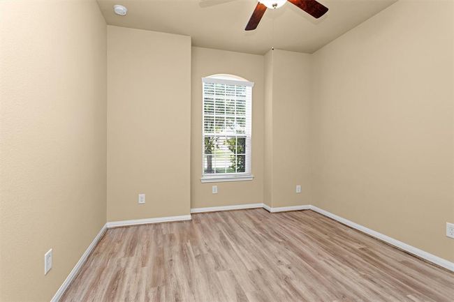 The second secondary bedroom offers a bright and welcoming atmosphere featuring luxury vinyl plank flooring, a large window, & a ceiling fan. | Image 20
