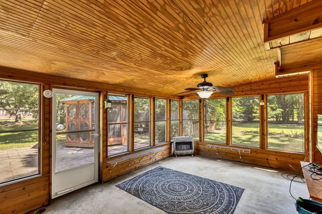 Sunroom featuring heating unit, roll up shades with screens and a ceiling fan | Image 23