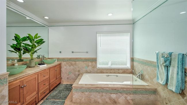 Master bath featuring double vanity, wainscoting, a garden tub, tile walls, and tile patterned floors | Image 20