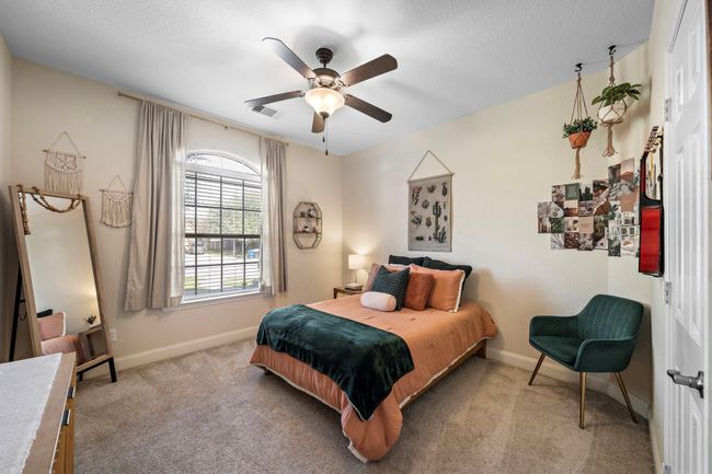 This cozy bedroom offers a restful retreat with large windows providing abundant natural light. Soft tones and plush carpeting enhance its welcoming atmosphere, making it an ideal space for relaxation or personalized decor. | Image 24