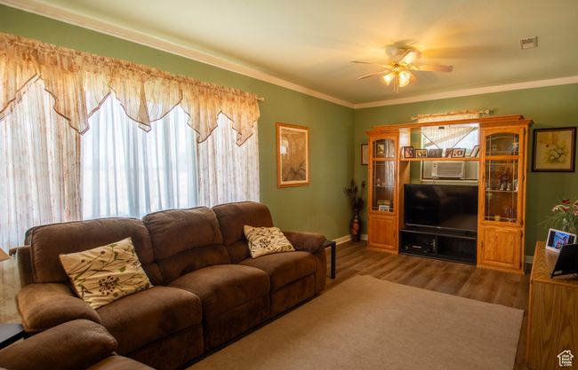 Living room featuring ceiling fan, wood finished floors, and ornamental molding | Image 11