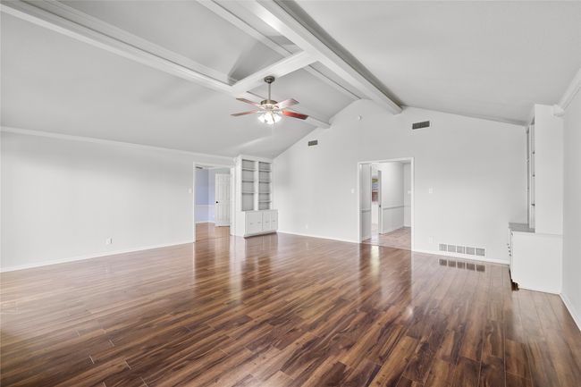 Unfurnished living room with a ceiling fan, wood finished floors, baseboards, and ornamental molding | Image 5