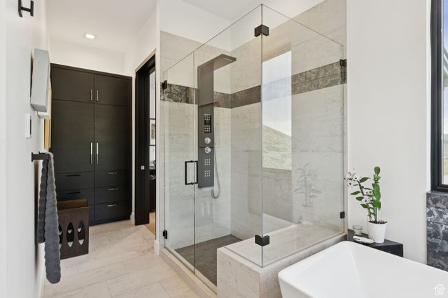 Bathroom with marble look tiles, a soaking tub, and a stall shower | Image 29