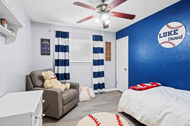 Bedroom featuring wood finished floors, ceiling fan, and a textured feature wall | Image 15