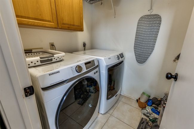 Laundry room with cabinet space, washing machine and dryer, and light tile patterned floors | Image 20