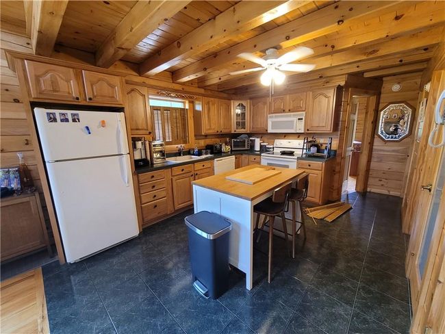 Kitchen with ceiling fan, dark tile flooring, wood ceiling, beamed ceiling, and white appliances | Image 10
