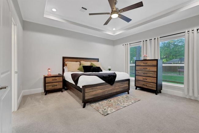 The spacious primary bedroom features an elegant en suite, stunning tray ceilings, and beautiful windows that frame peaceful views of the backyard. | Image 24