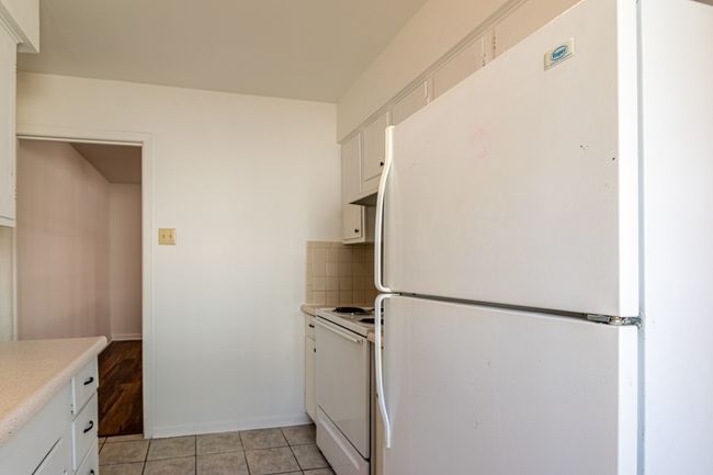 1214 Hunt - Kitchen with light tile patterned flooring, light countertops, white cabinetry, tasteful backsplash, and white appliances | Image 7