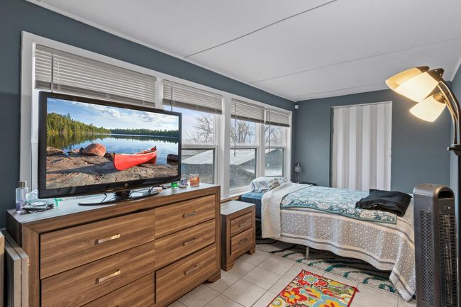 Bedroom one, which could also serve as a sunroom, is lined with windows that invite natural light, offers ample closet space, features tile flooring, and provides direct access to the 14x8 deck. | Image 7