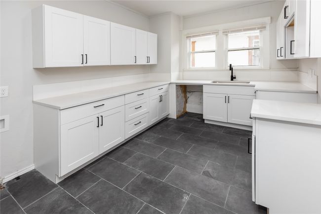 Kitchen with a sink, white cabinets, and light countertops | Image 6