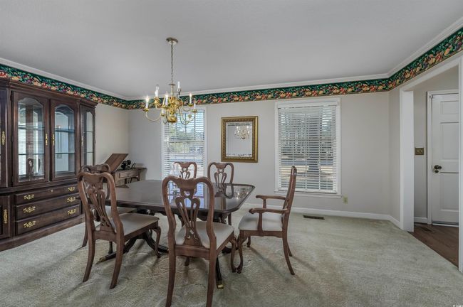 Dining space featuring carpet floors, crown molding, and an inviting chandelier | Image 12