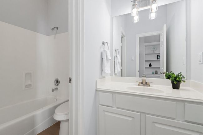 This spacious bathroom features a separate water closet-style layout, with a door dividing the toilet and tub area from the main vanity space—perfect for added privacy and functionality. The layout allows for comfortable, shared use. | Image 16