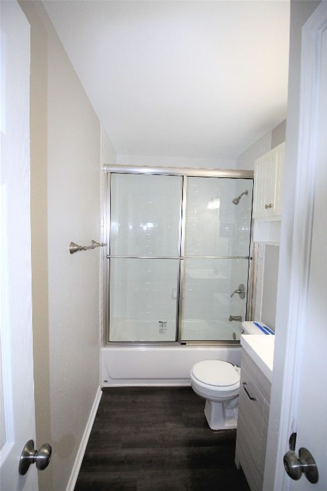 Full bathroom with wood finished floors, vanity, and bath / shower combo with glass door | Image 10