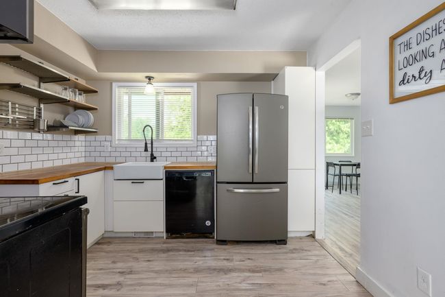 Kitchen featuring freestanding refrigerator, wood counters, dishwasher, and a sink | Image 15