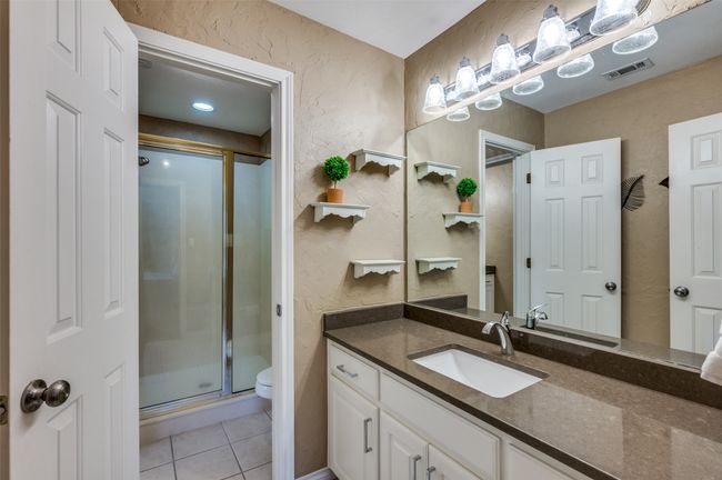 Full bathroom with a textured wall, a shower stall, toilet, vanity, and tile patterned flooring | Image 18